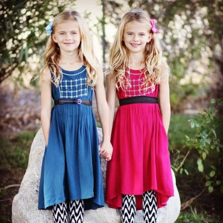 Baylie Cregut and her identical twin sister Rylie Cregut holding hands.